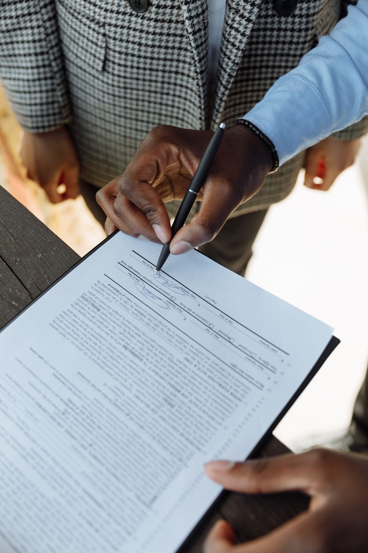 A person signing a business contract with a pen, agreeing to its terms
