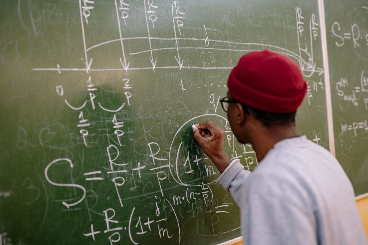 A student solving a math problem at the chalkboard in class